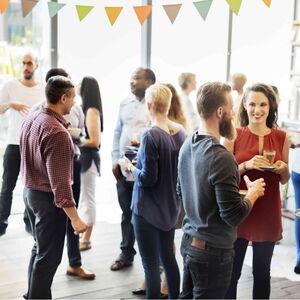 Angst vor Nähe ablegen und den Kontakt zu anderen Menschen wieder geniessen. Eine Gruppe von Menschen steht in einem Raum auf einer Party. Ein Mann steht etwas abseits. Er hat noch nicht den Mut Kontakt zu den anderen aufzunehmen.