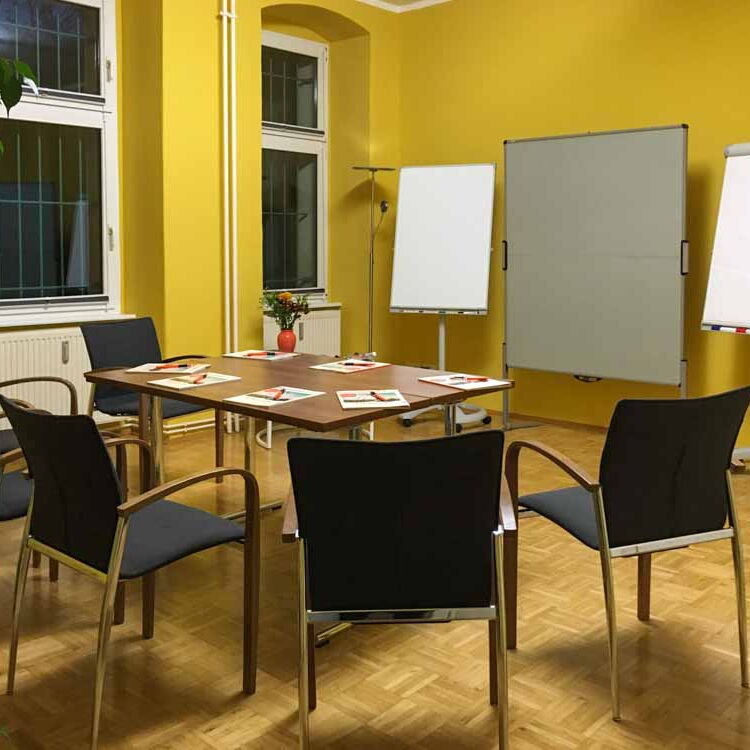 Der große Raum in der Coachingpraxis mit Seminarbestuhlung, Tischen, Flipcharts und Metaplanwänden.