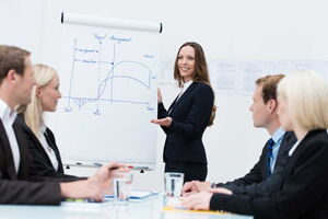 Ohne Vortragsangst vor Gruppen stehen und seine Ideen präsentieren. Eine Frau steht vor einer Businessgruppe und präsentiert ihre Ideen.